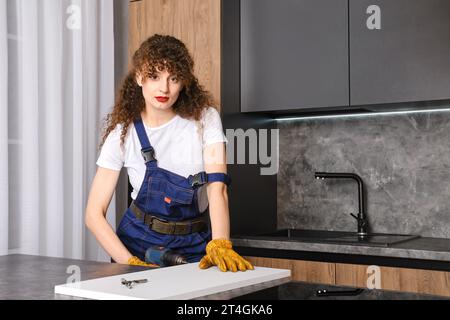 Woman drilling a hole in a chipboard panel in the kitchen Stock Photo