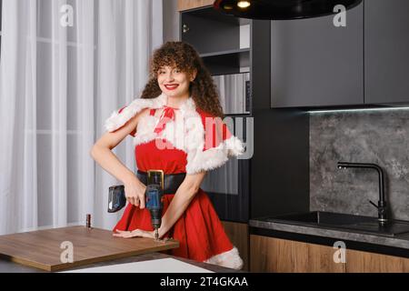 Smiling snow maiden installing hinges on kitchen cabinet door Stock Photo