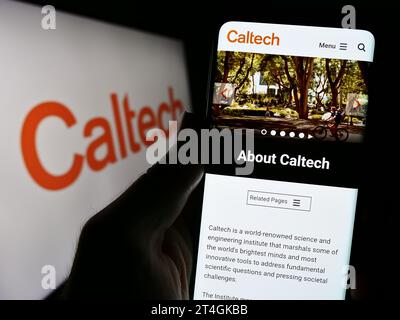 Person holding smartphone with webpage of university California Institute of Technology (Caltech) with logo. Focus on center of phone display. Stock Photo