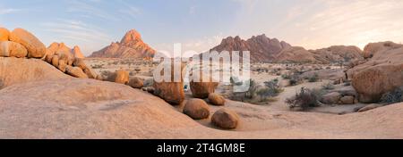 Panoramic, desert landscape of famous rounded red, granite rocks of Spitzkoppe area in early sunrise against blue sky. Picturesque rocky desert photo Stock Photo