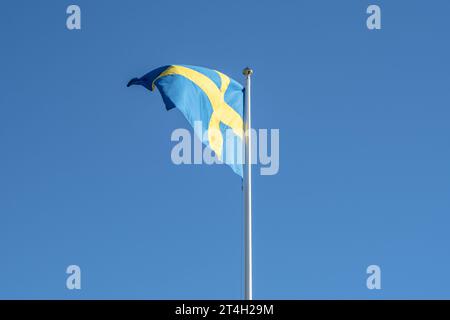 Swedish flag waving in the wind in Stockholm on the national day against a blue sky. Stock Photo