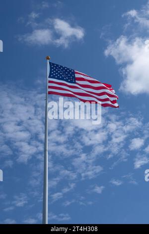 The stars and stripes flag of the United States of America, flapping in the wind on a partially cloudy day. Stock Photo