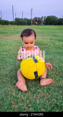 cute infant playing with football at green grass field from different angle Stock Photo