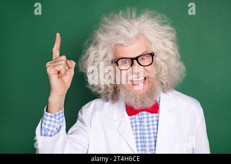 Portrait of astonished cheerful doctor point finger beaming smile look camera isolated on dark green color background Stock Photo