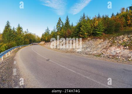 road through forested hill of apuseni natural park, romania. autumnal mountainous landscape in morning light Stock Photo