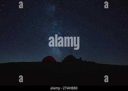 Camping night sky Milky Way above tents silhouette Stock Photo