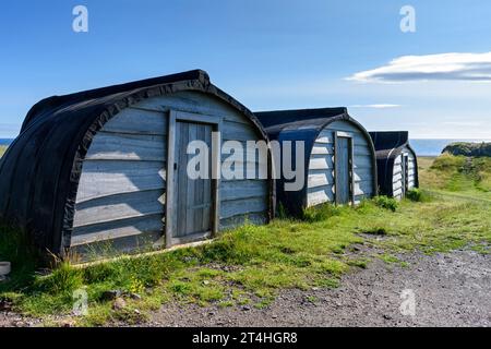 Three of the traditional sheds made from upturned boats, near the entrance to Lindisfarne Castle, Holy Island, Northumberland, England, UK. Stock Photo