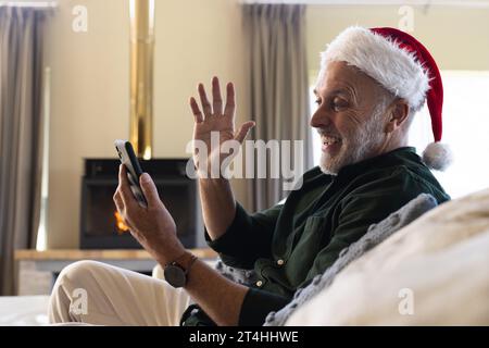 Happy senior caucasian man sitting on sofa having christmas video call at home Stock Photo