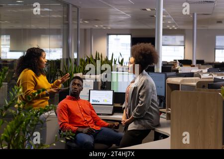 Three diverse casual businesspeople discussing and using tablet in office, copy space Stock Photo