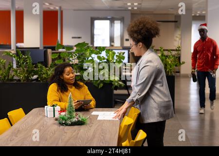 Two diverse casual businesswomen discussing and using tablet in office, copy space Stock Photo