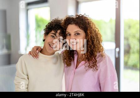 Portrait of smiling mother and son standing in living room at home Stock Photo