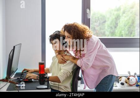 Mother and son looking at computer monitor at home Stock Photo