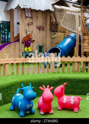 Interior of part of the facilities offered at Monty's Farm Park's play barn with pink and blue toys for toddlers in the foreground Stock Photo