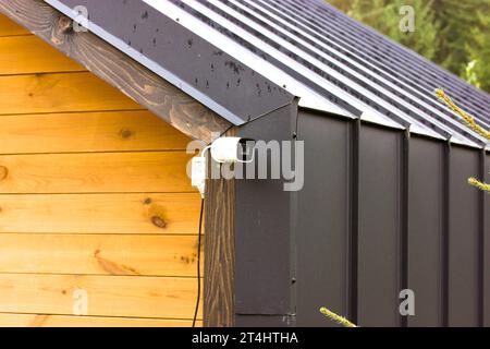 CCTV rotating surveillance video camera on a cottage house. Home security system Stock Photo