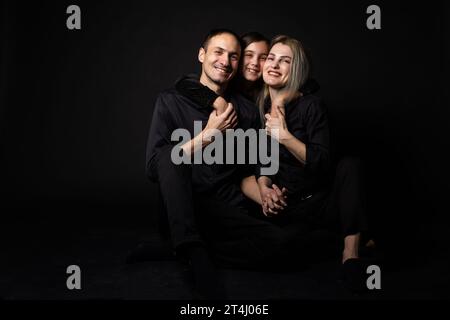 Happy young family with one child having fun together isolated on black. Stock Photo