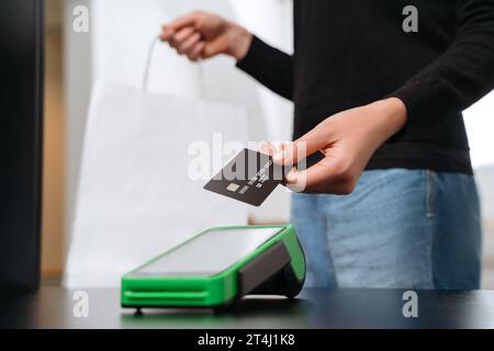 Hand of woman customer using wireless or contactless payment by credit card, girl making shopping. NFC technology at retail shop. Contactless payment concept Stock Photo