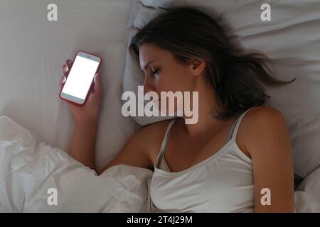 Smartphone is lying in womans hand while she sleeping. Smartphone and social networks dependence. Gadget and internet addiction concept. Insomia and unhealthy sleep. Stock Photo