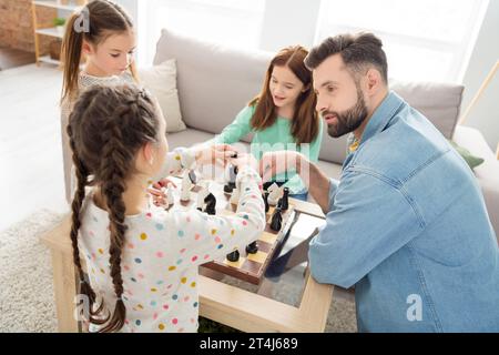 Portrait of attractive intellectual focused idyllic family playing chess with daddy learn study at home house living-room indoors Stock Photo