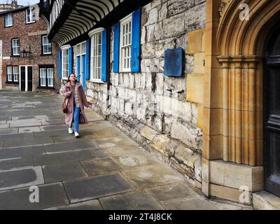 Young woman with shoulder length brown hair walking past St Williams College in York Yorkshire England Stock Photo