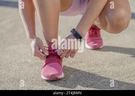 Close-up of a girl in sportswear tying her shoe laces. Stock Photo