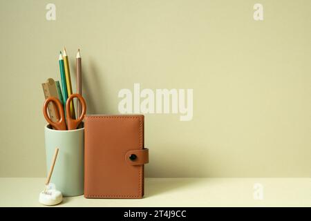Notebook and writing supplies pencil holder on desk. khaki beige background Stock Photo