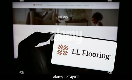 Person holding smartphone with logo of US retail company LL Flooring in front of website. Focus on phone display. Stock Photo