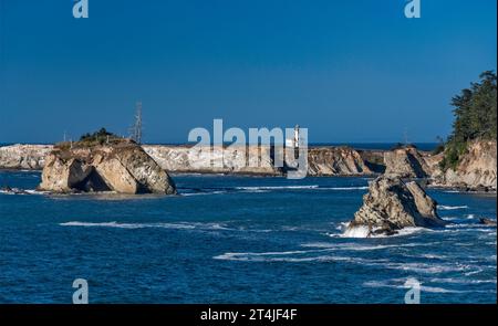 Cape Arago Lighthouse in distance, deposits of guano on rocks, near Charleston, Oregon, USA Stock Photo