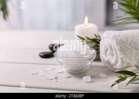 composition with sea salt, towel and candle on white wooden table at spa centre. copy space Stock Photo