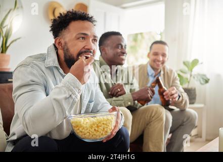 We enjoying a good movie night now and then. three male friends watching something together while sitting on a couch. Stock Photo