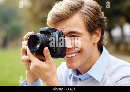 Hold that pose for me. a young man taking photos in a park. Stock Photo