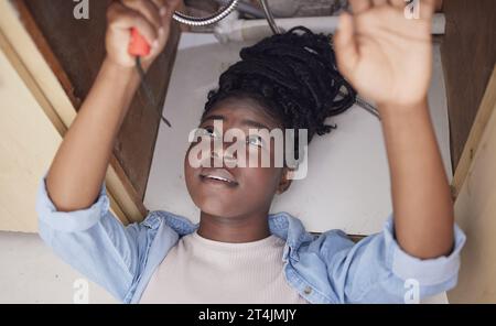Nothing in the world can take the place of perseverance. a young woman installing a kitchen sink at home. Stock Photo