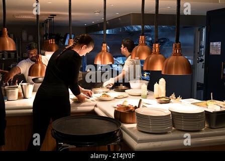 Restaurant chefs serving area with waitress collected food which is ready, Gusto Italian, Oxford, UK Stock Photo