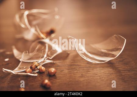 Close-up of a broken transparent glass of compote with raisins. Pieces of broken glass lie on the floor with space to copy. High quality photo Stock Photo