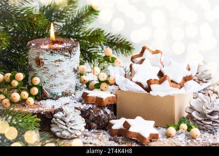 Christmas cookies in star shape and burning candle surrounded fir branches Stock Photo