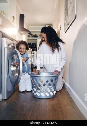 Adorable little African American boy with an afro smiling and faving fun while doing housework with him mother at home. mixed race portrait of a cute Stock Photo