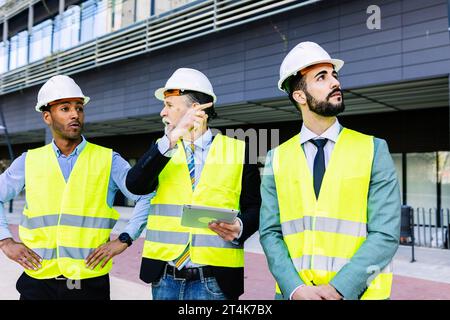 Three construction engineers having a discussion on building site. Stock Photo
