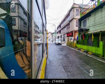 view outside toy train in darjeeling shimla showing the wet street and cars moving on the road showing this famous attraction Stock Photo