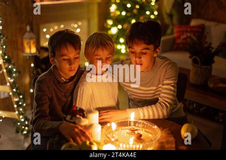 Three children, lighting candles in a nutshell, czech Christmas traditions, decorated room, family traditions Stock Photo