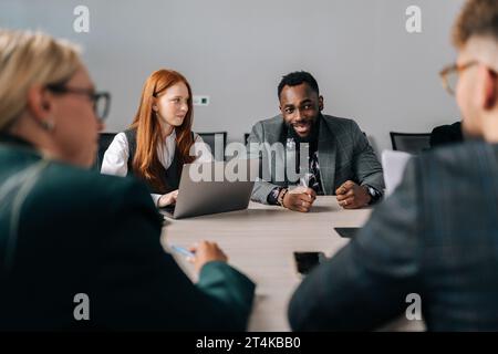 Back view of diverse business team brainstorm on project during corporate meeting. Multiracial employees listening colleague sharing idea, discuss new Stock Photo