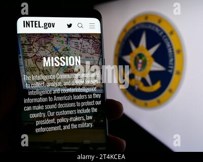 Person holding smartphone with web page of agency group United States Intelligence Community (IC) with seal. Focus on center of phone display. Stock Photo