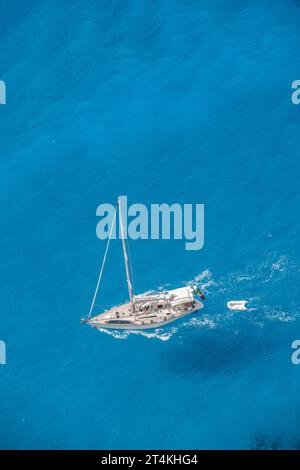 Sailing yacht crossing an azure, turquoise sea on the Greek Ionian island of Zante or Zakynthos in Greece. Stock Photo