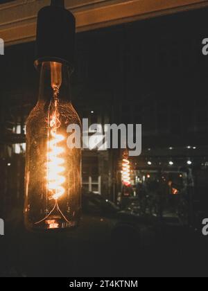 light bulb illuminating a dark room with reflection on window Stock Photo