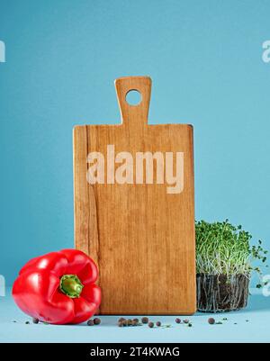 still life with wooden cutting board and vegetables on blue background Stock Photo