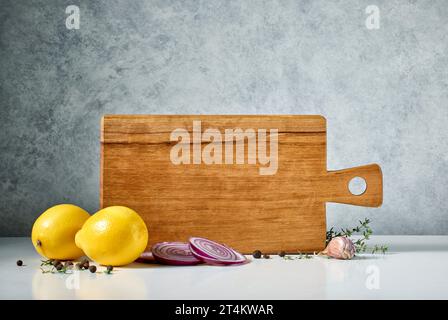 still life with wooden cutting board and spices on grey background Stock Photo