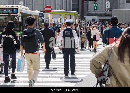 Tokyo, Japan - April 11, 2023: busy pedestrian crossing with unidentified policeman and crowds in Shibuya. Shibuya is a major commercial and finance c Stock Photo