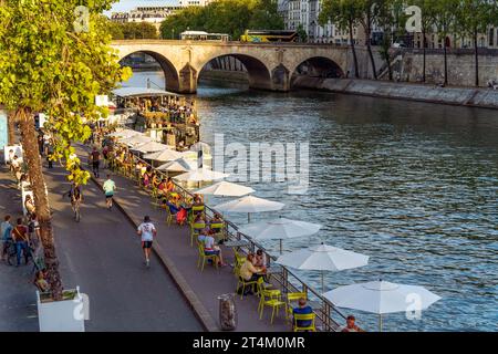 Lively quay along the Seine river with people enjoying time outside, relaxing and running, in summer, Paris city centre, France Stock Photo