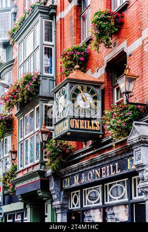 Colorful façade of traditional O'Neills Pub in Dublin, with vintage clock and hanging baskets, in Dublin city centre, Ireland Stock Photo