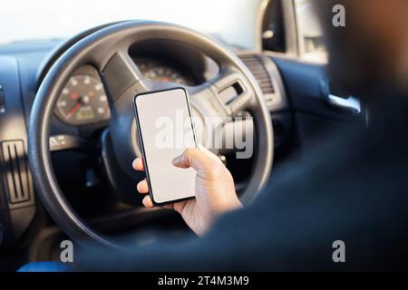 The only impossible journey is the one you never begin. a young man sitting in a car while using his phone. Stock Photo
