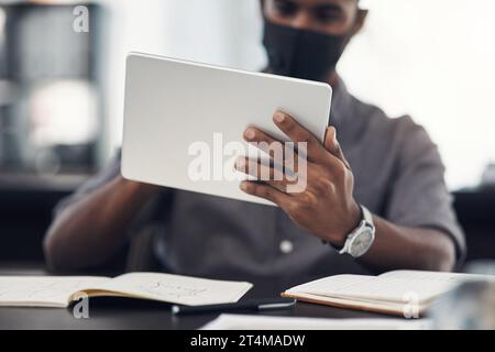 Using the latest apps to boost workplace performance. Closeup shot of an unrecognisable businessman using a digital tablet in an office. Stock Photo