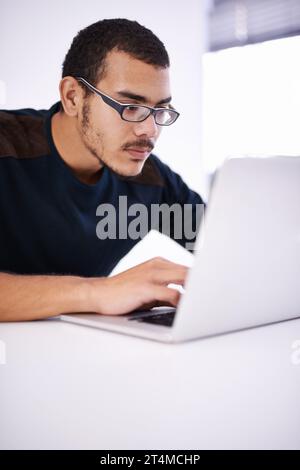 Working hard on a brand new design. a handsome young man working on his laptop in an office. Stock Photo